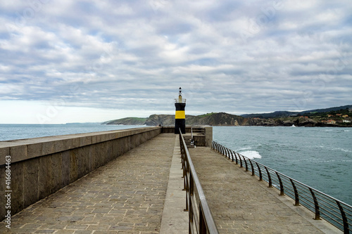 view of the dike and the ligthouse at comillas, cantabria spain photo