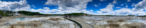 YELLOWSTONE, MONTANA - JULY 10, 2019: Tourists visit the famous geysers and pools on a beautiful summer day - Panoramic view