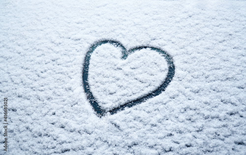 snow background with frozen heart on the glass