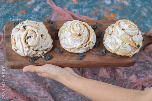 Fried meringue cookie with black raisines on a wooden board photo