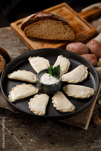 Appetizing traditional Russian dumplings, hand-made with potatoes. Still life on a wooden board. Close-up. photo