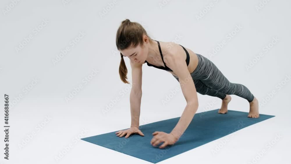 Young girl performs synchronous bends of the arms in the bar position. The girl is engaged in sports, fitness. Active lifestyle. Isolated on a white background Young girl performs synchronous bends of the arms in the bar position. The girl is engaged in sports, fitness. Active lifestyle. Isolated on a white background
