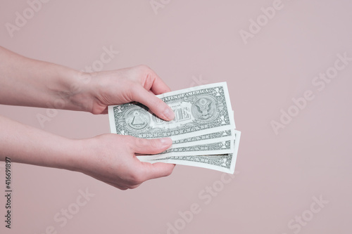 Female hand holding one dollar banknotes. Allowance and financial help concept