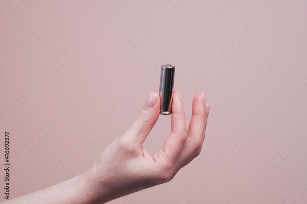 Hand holding metallic alkaline battery Hand holding metallic alkaline battery