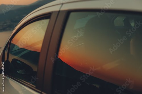 Sunset reflection on car window in twilight. Red and orange colors.