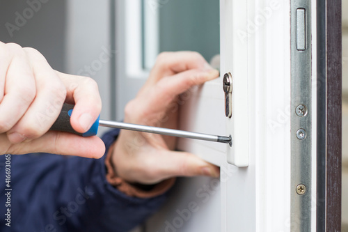 Handyman installing door lock in front door. Checking the door lock with a screwdriver for operability. photo