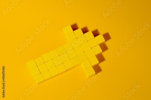 Arrow made with yellow wooden blocks. Closeup, top view. Abstract business and leadership concept