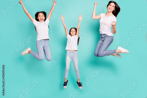 Full length body size photo sisters jumping overjoyed won lottery keeping hands up happy funny isolated vivid blue color background