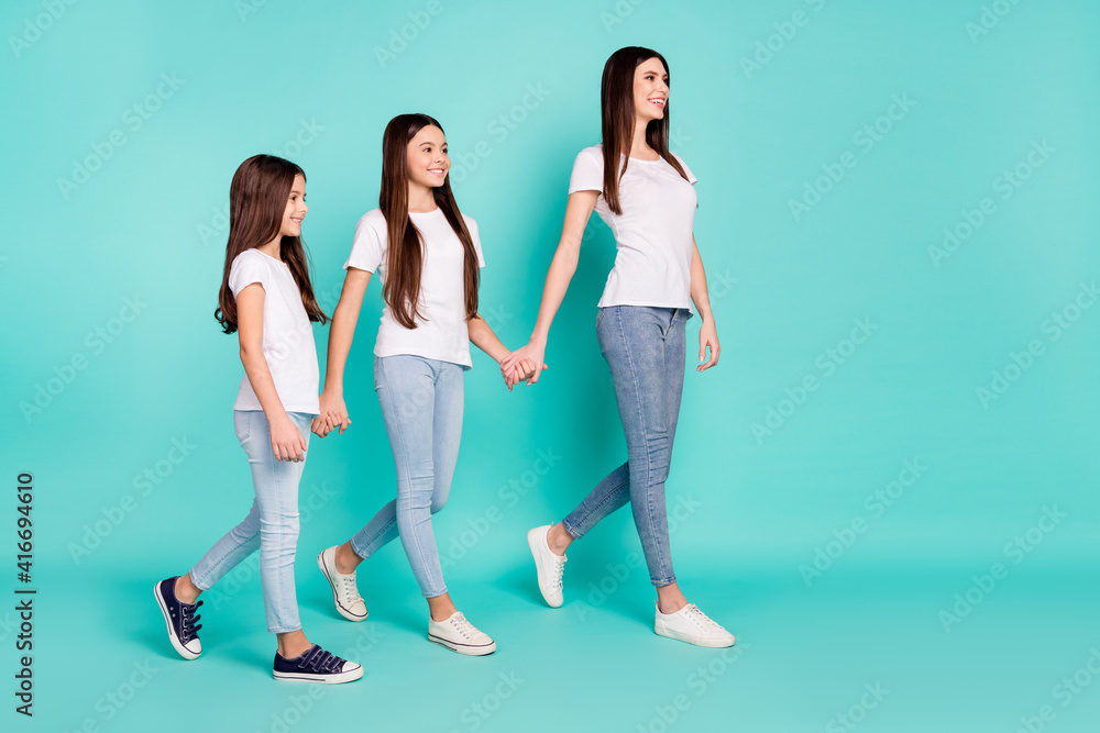 Fototapeta premium Full length body size photo of three sisters going forward holding hands looking copyspace isolated vibrant blue color background
