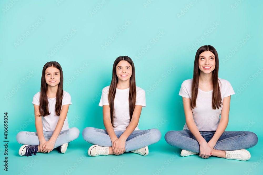 Full length body size photo of three sisters sitting in lotus pose smiling looking up dreamy isolated vivid blue color background Full length body size photo of three sisters sitting in lotus pose smiling looking up dreamy isolated vivid blue color background