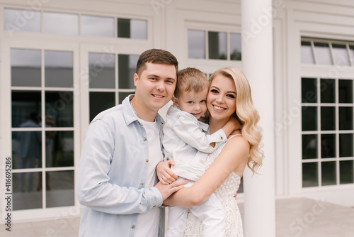 Beautiful young family man woman and son in smart clothes on the background of a luxurious white house © ksyusha_yanovich