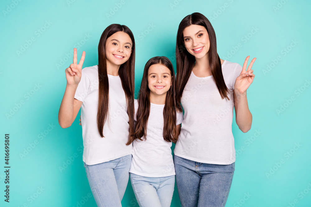 Photo portrait of three young sisters in white t-shirts showing peace v-sign gestures isolated vibrant blue color background Photo portrait of three young sisters in white t-shirts showing peace v-sign gestures isolated vibrant blue color background