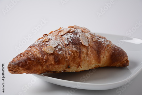 Traditional French breakfast croissant with almonds on white background