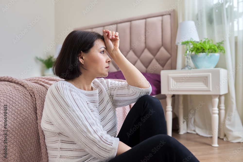 Unhappy tired depressed mature woman sitting at home on the floor Unhappy tired depressed mature woman sitting at home on the floor