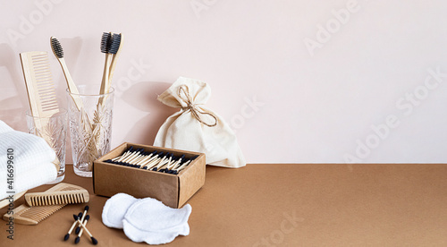 Eco friendly lifestyle concept. Zero waste products for the home. Contemporary still life with biodegradable bamboo toothbrushes, bamboo ear sticks, wooden combs and reusable cotton sponges photo