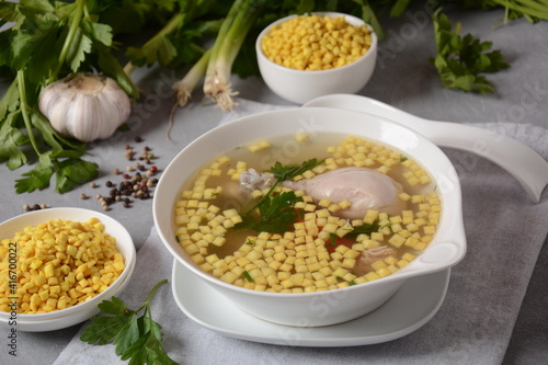 Chicken soup , chicken broth, with pieces of chicken and vegetables and shkedei marak an Israeli food product crisp mini croutons used as a soup accompaniment