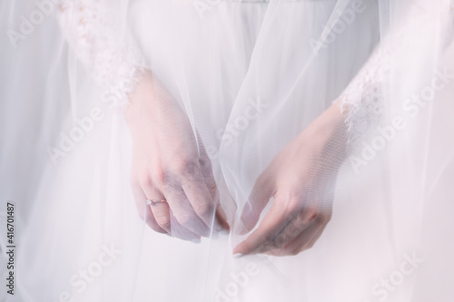 Bride hand with a beautiful diamond ring on a white dress covered with a veil © Ivan