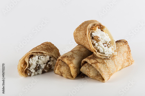 Several pancakes stuffed with cottage cheese with raisins on a white background close-up with a copy space for the text, isolated.