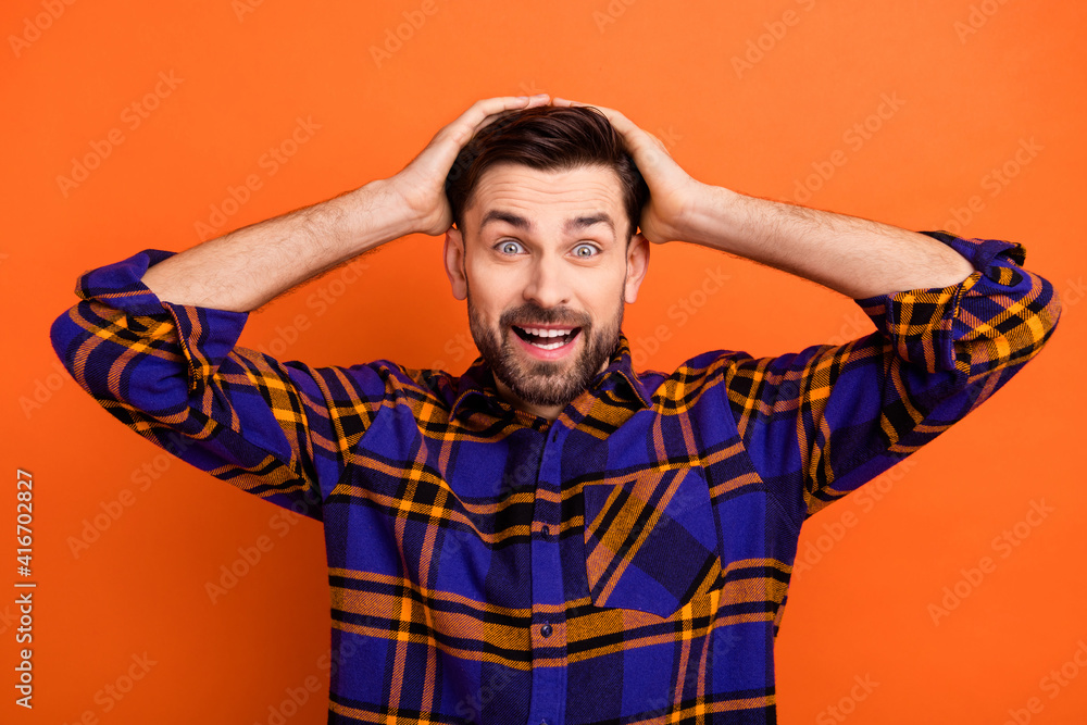 Photo of young excited man happy smile hands touch head amazed shocked surprised news sale isolated over orange color background Photo of young excited man happy smile hands touch head amazed shocked surprised news sale isolated over orange color background