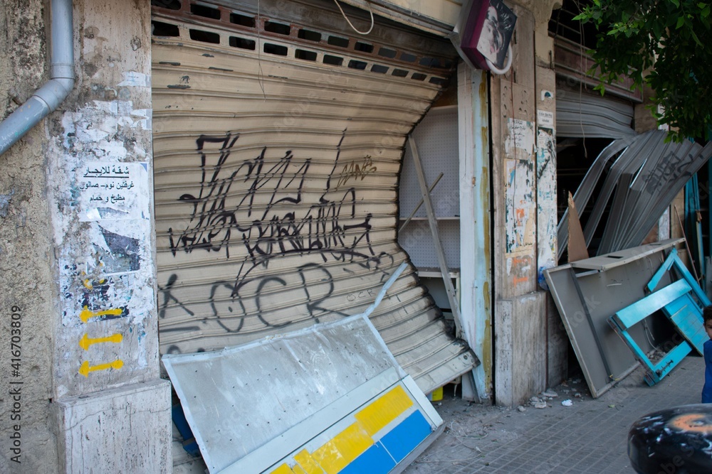 Naklejka premium Metal shutter at a storefront in Beirut deformed from the shockwave of an explosion in August 2020