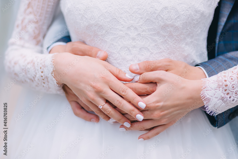 detail of hands of newlyweds at wedding displaying gold wedding rings.