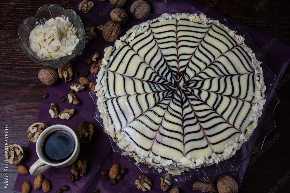 Delicious esterhazy cake with nuts, almonds, black and white chocolate and a cup of coffee on a dark background top view copy space, close up