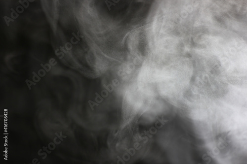 steam in a beam of light from a boiling kettle on a dark background