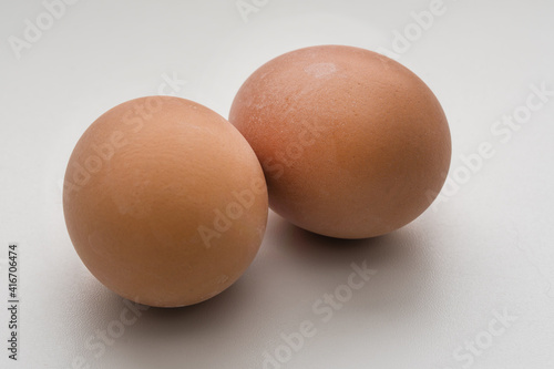 Two boiled or raw fresh eggs in yellow shell isolated on white background