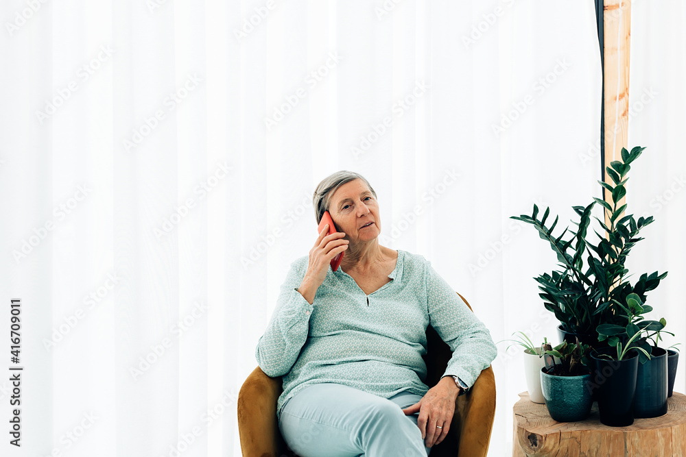 old woman speaking on the phone in a bright light interior design