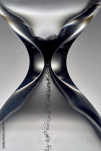 Hourglass with pouring dark sand. The last grains of sand.