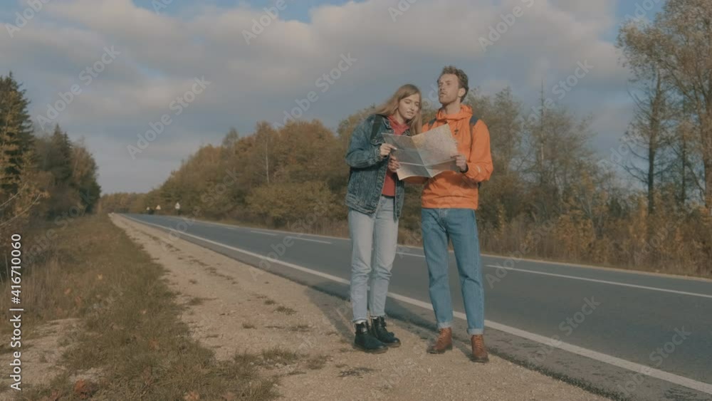 Young woman and man backpackers looking at a map. Road trip. Young woman and man backpackers looking at a map. Road trip.