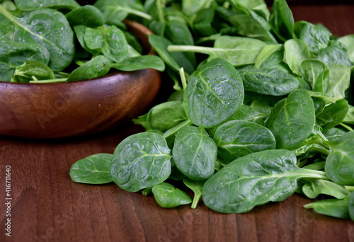Fresh baby spinach leaves on a wooden background stock images. Fresh green spinach in a wooden bowl. Healthy leafy vegetables on the table close-up stock photo