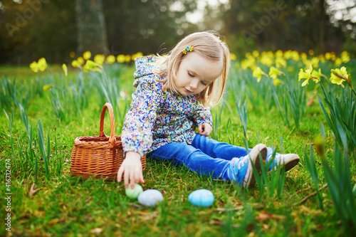 Three year old girl playing egg hunt on Easter