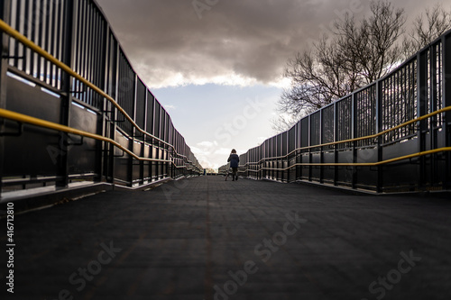 Young girl walking out of the darkness into the light at the end symmetrical rails depressing looming storm cloud skyline walk towards sunlight and hope better times ahead © Matthew