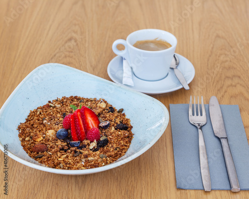 Muesli bowl with berries on top served with a cup of espresso on the side. Perfect breakfast in the morning.