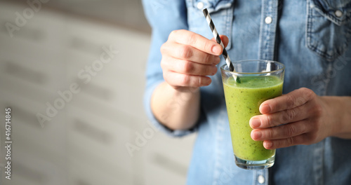 Woman with delicious kiwi smoothie indoors, closeup. Space for text