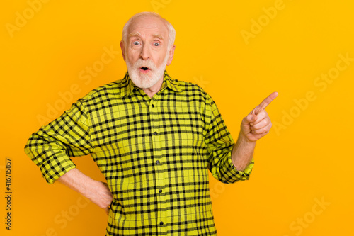 Photo of old man amazed shocked indicate finger empty space ad promo suggest sale isolated over yellow color background
