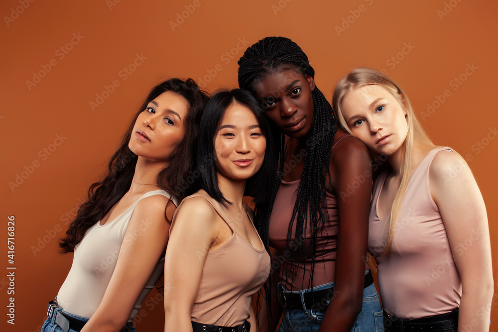 Fototapeta premium young pretty asian, caucasian, afro woman posing cheerful together on brown background, lifestyle diverse nationality people concept