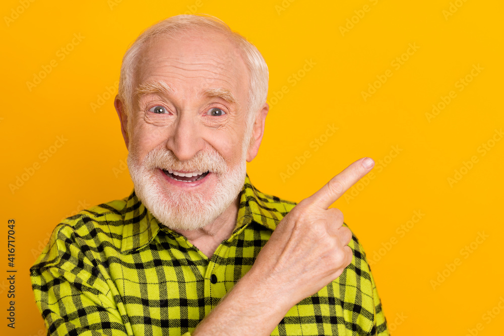 Photo of elderly man happy smile indicate finger empty space advert promo recommend advise isolated over yellow color background Photo of elderly man happy smile indicate finger empty space advert promo recommend advise isolated over yellow color background