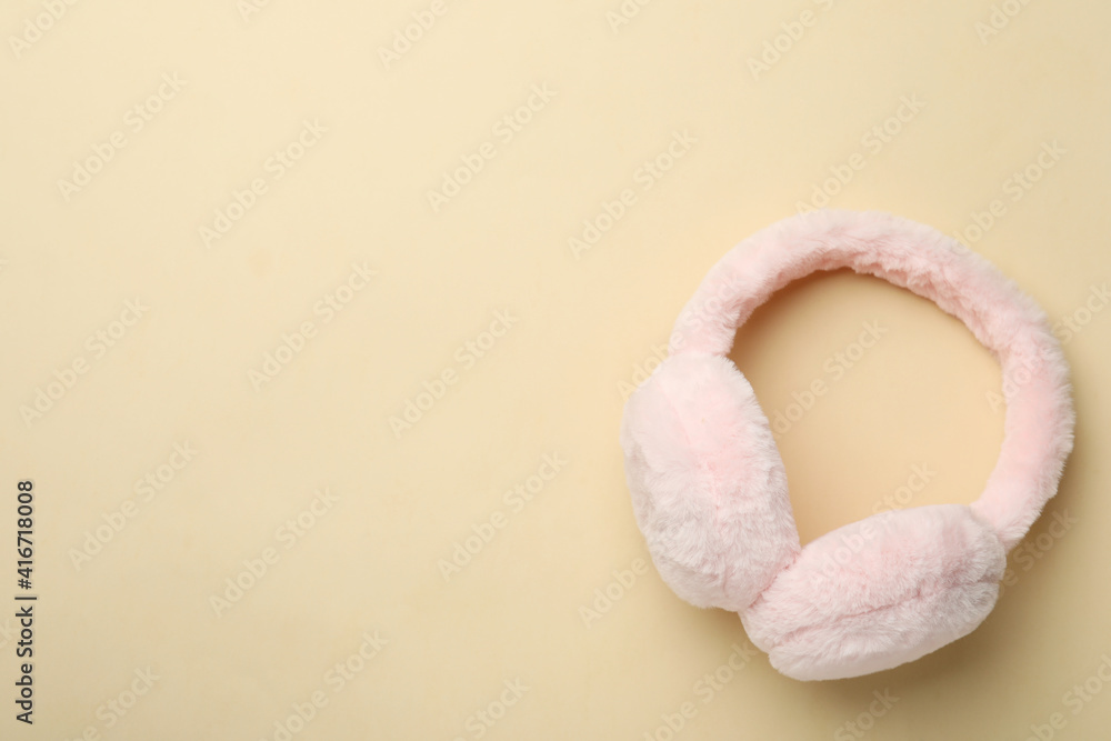 Stylish warm earmuffs on beige background, top view. Space for text