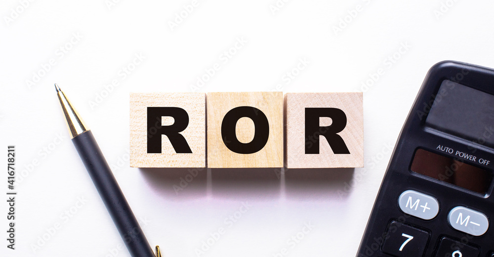 The word ROR is written on wooden cubes between a pen and a calculator on a light background. The word ROR is written on wooden cubes between a pen and a calculator on a light background.