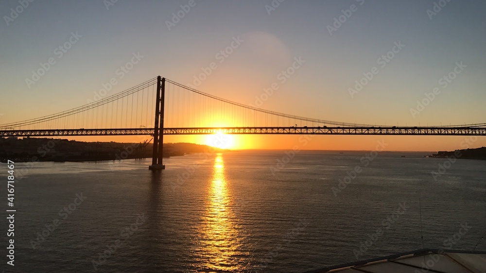 Obraz premium Portugal Lissabon Brücke des 25. April Hängebrücke Metall über dem Fluss Tejo von einem Kreuzfahrtschiff aus am Morgen bei Sonnenaufgang am Horizont