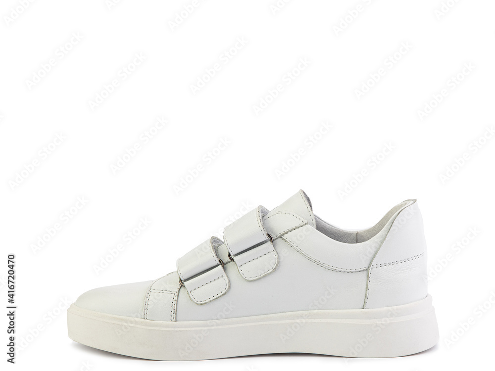 White leather sneakers with velcro in front instead of laces. Casual women's style. White rubber soles. Isolated close-up on white background. Left side view. Fashion shoes.