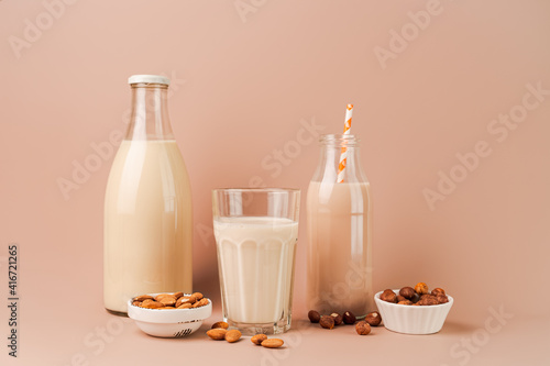 Various vegan plant based milk and ingredients. Dairy free milk substitute drinks on pink background