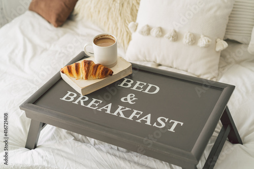 Tray with croissant and cup of coffee in white clean bed. Mindful and quiet living.
