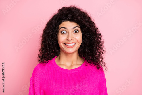 Portrait of young happy crazy excited delighted shocked woman smiling with wavy hair isolated on pink color background