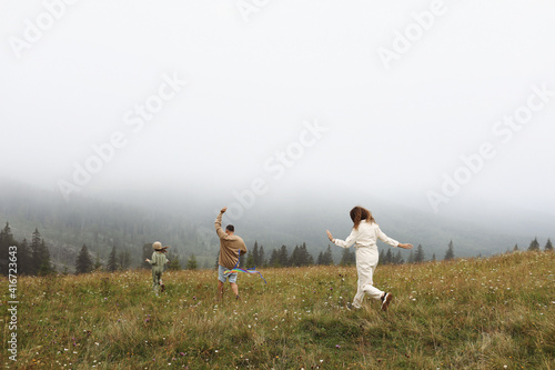 Happy family concept. parents and child are playing with a colorful kite. Young mother  father and their little cute daughter having fun together outdoors in foggy day. mothers  fathers  baby s day