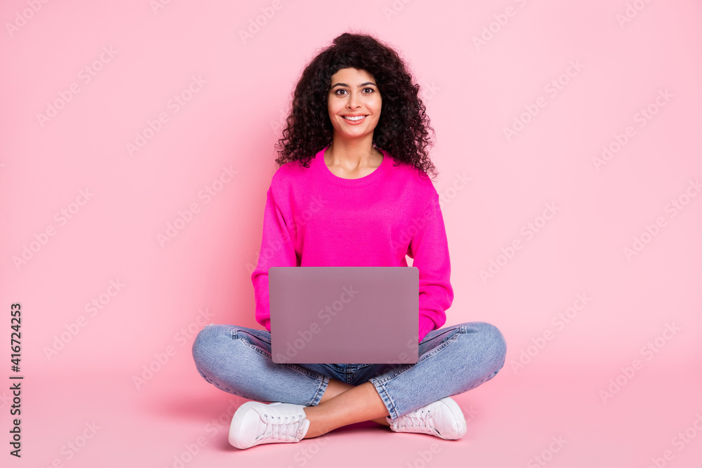 Naklejka premium Full size photo of young happy lovely pretty smiling girl sit floor working in laptop look camera isolated on pink color background