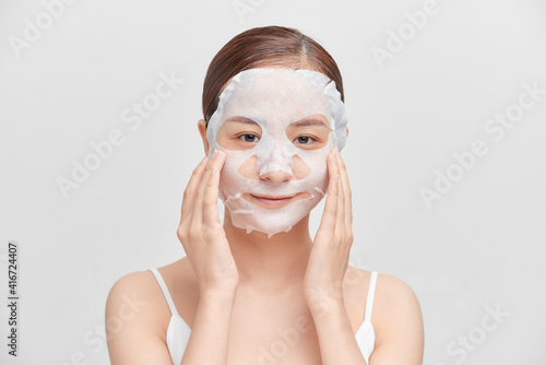 Happy young Asian woman using cosmetic mask isolated over white background.