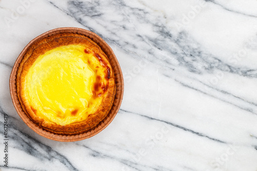 Egg tart, traditional Portuguese dessert, pastel de nata in a gray plate on a marble background . Portuguese puff close-up. Selective focus, copy space
